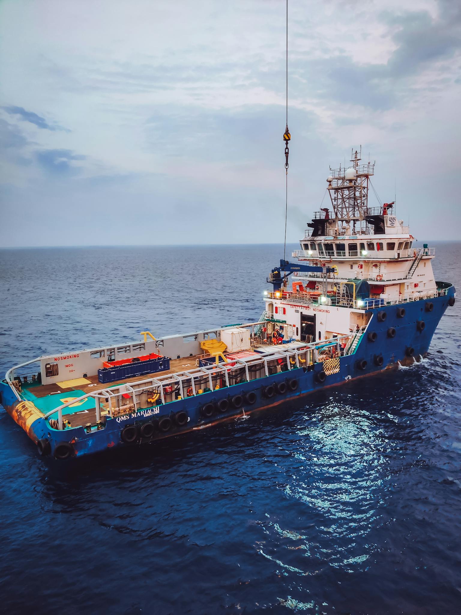A drone captures a tugboat navigating the vast ocean under a clear blue sky.